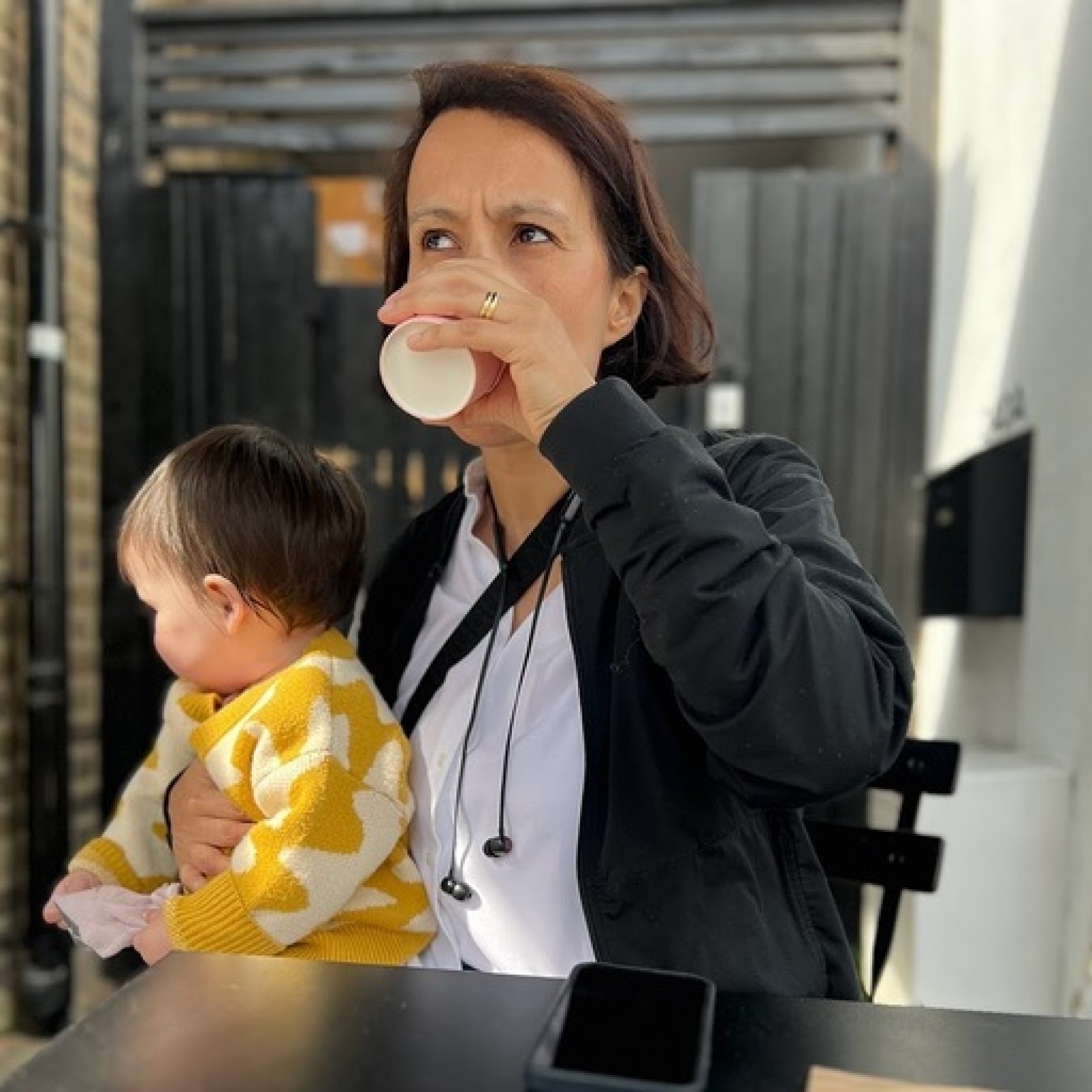 Inayaili León drinking tea while holding her child